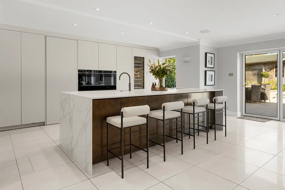 Spacious neutral kitchen with dark wood island, four bar stools and tall cabinetry