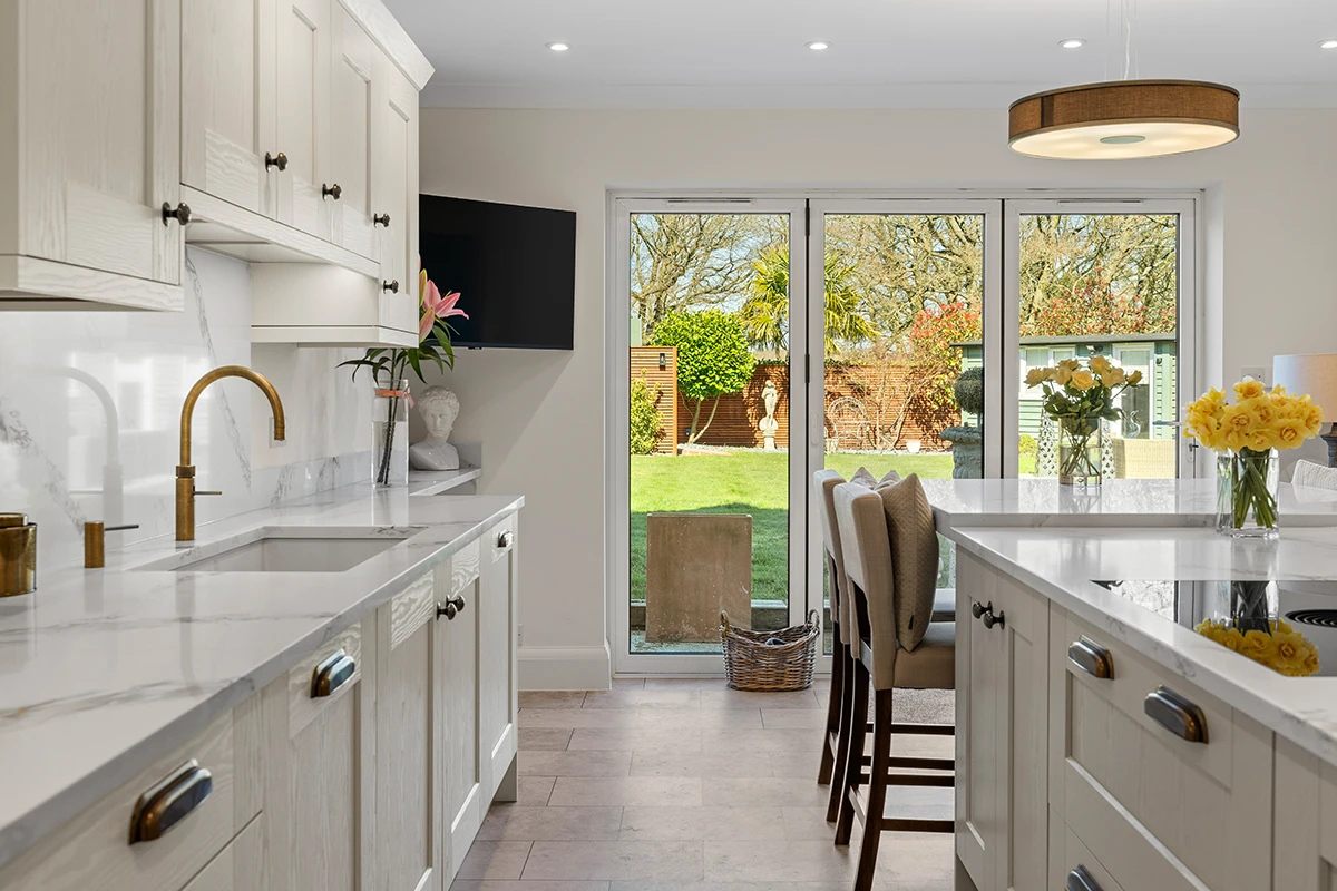 Light traditional kitchen with long island and glazed doors to the garden