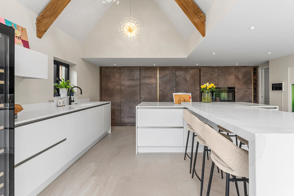Contemporary white kitchen beneath exposed timber beams with central island