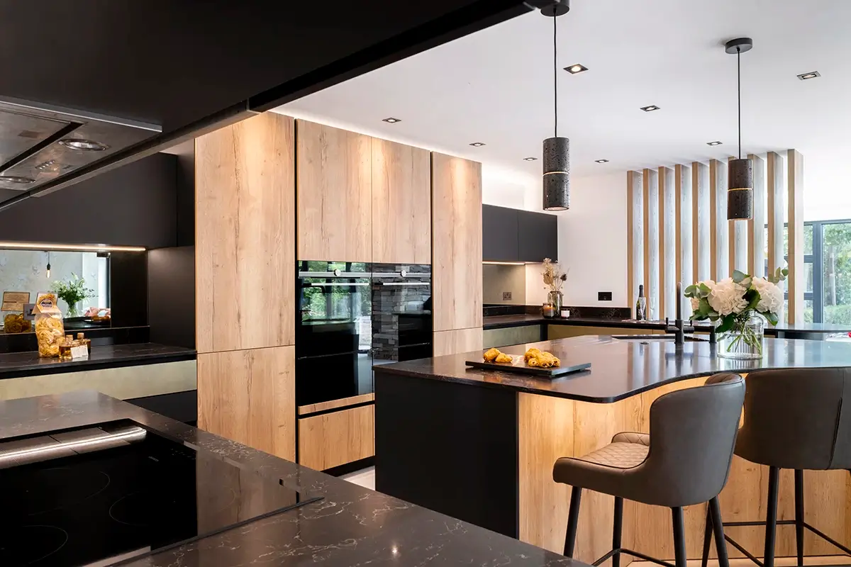 Dark kitchen island with bar stools and timber-fronted cabinets in an open-plan room