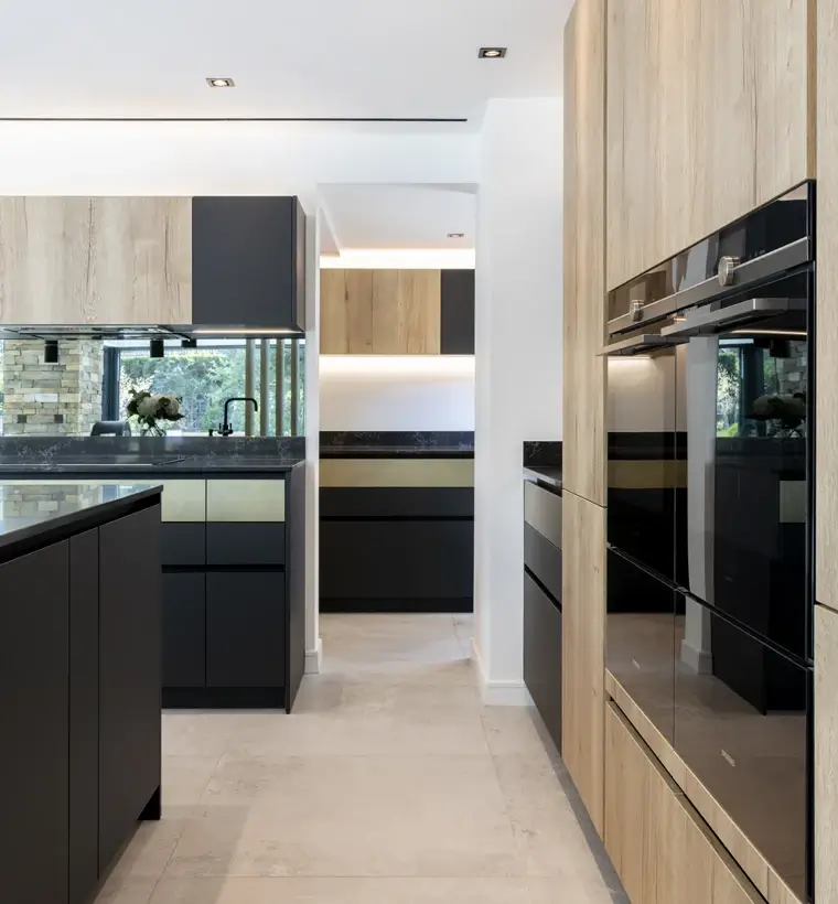 Contemporary kitchen with dark island and integrated appliances in tall cabinets