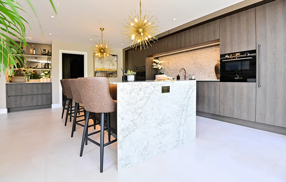 White kitchen island with bar stools facing dark wood cabinets and glazed garden doors