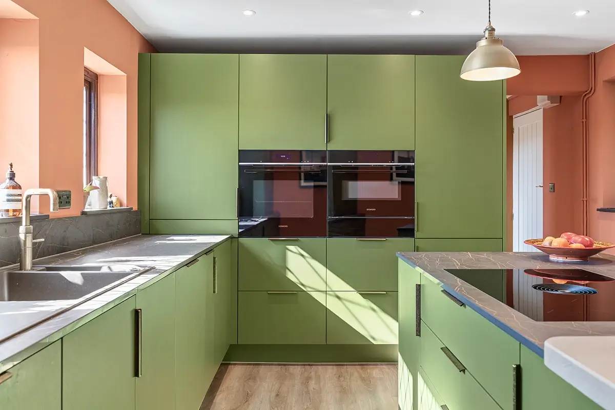 Green galley kitchen with integrated ovens and a central island